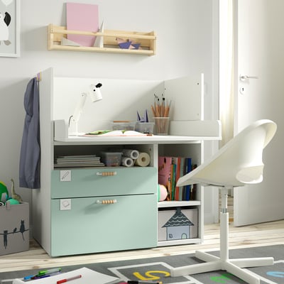 Children’s desk and chair setup. White desk with mint drawers, organised with art supplies. Realizaable for play and study.