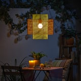 Cosy outdoor seating with hanging light, plant, and candle, creating warm ambiance.