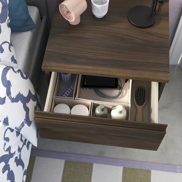 Open bedside drawer with toiletries and phone.