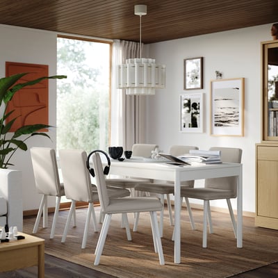 Modern dining room with TONSTAD white table, six beige chairs, wooden decor, and large window.