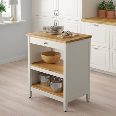 A TORNVIKEN white kitchen island with light wood, featuring storage shelves and a workspace.