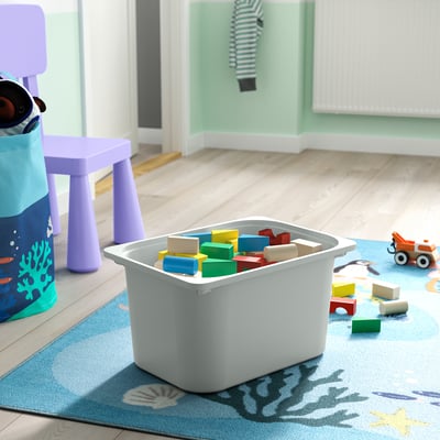 A white plastic storage box filled with colourful toys on a blue rug, ideal for storing childrens items.