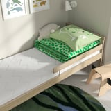 Childrens bed with a green, dinosaur-patterned mattress. Light wood frame fits perfectly, providing a cosy sleep space.