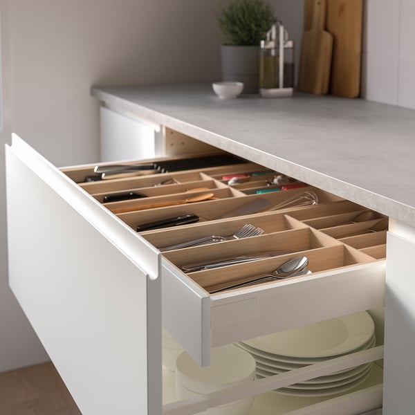 Open kitchen drawer showing organised cutlery in bamboo tray, with plates below.