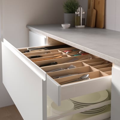 Open kitchen drawer showing organised cutlery in bamboo tray, with plates below.
