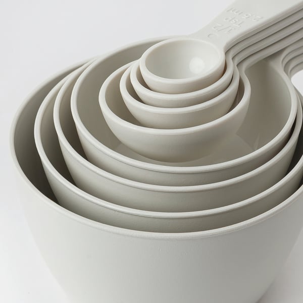 Set of measuring cups nested together, white, smooth texture, easy to stack & store.