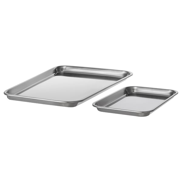 Two stainless steel baking trays, one larger, one smaller, both rectangular with raised edges, placed diagonally against a white background.