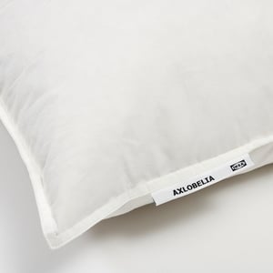 Close-up of a soft, white pillow with AXLOBELIA brand tag, high-quality cotton and feather filling, ideal for side or back sleepers.
