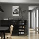Modern dining area with sideboard, dishes, decor, art, and shelves. Light wooden floor.