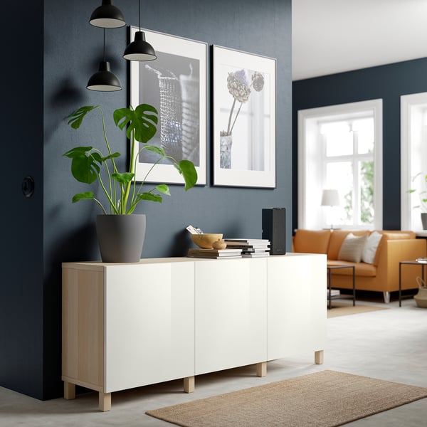 White BESTÅ sideboard in living room with plant, art, & sofa.