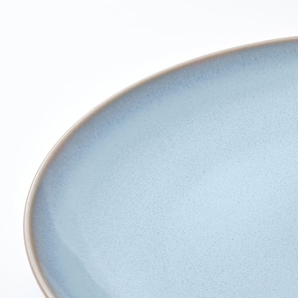 Close-up of smooth, cerulean blue stoneware dish on white surface.