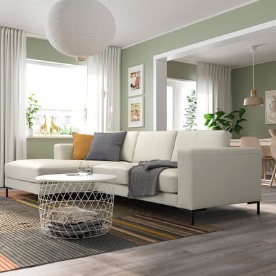Modern living room with light beige leather FULLERÖ 3-seater sofa and chaise, white coffee table, large pendant lamp, light green walls.