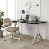 Black IDÅSEN adjustable desk, white base, beige chair, lamp, laptop, cup & whiteboard. Neat, efficient workspace for work & study.