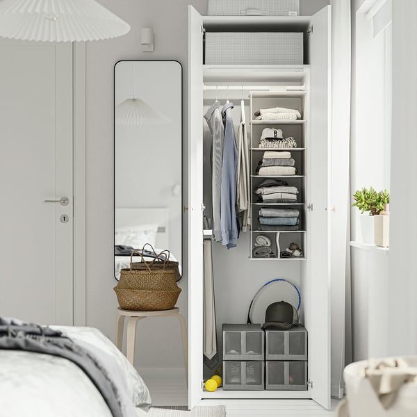 An open, organised wardrobe with hanging clothes, folded items, and storage cubes at the bottom, illuminated by internal lighting.