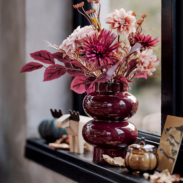 Maroon PÄRLHÄGG vase with pink burgundy flowers on shelf.