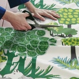 Řezání zelené listové látky z kolekce ikeas ÄLGÖRT pro šití projektů.