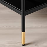 Moderní černo-zlatá noha stolu na dřevěné podlaze.
