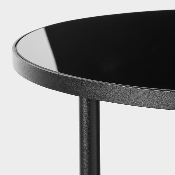 Moderní kulatý stůl s elegantní černou skleněnou deskou, navržený pro odolnost a styl.