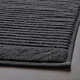 Detailní záběr tmavě šedé froté koupelnové předložky, která ukazuje její strukturovaný, savý povrch a pevnou vazbu.