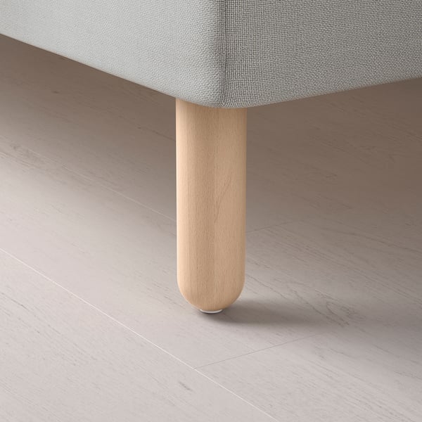 Detailní záběr na lehkou dřevěnou nohu stolu na podlaze, která ukazuje jemné řemeslné zpracování a přírodní povrchovou úpravu.