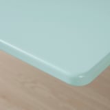 Hladký, světle modrý okraj stolu, mírně zaoblený, čistý povrch na dřevěné podlaze.