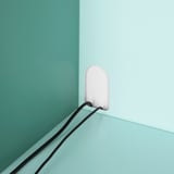 Pastelově růžová lampa na světle modré stěně s černým akordem, předvádějící moderní minimalistický design.