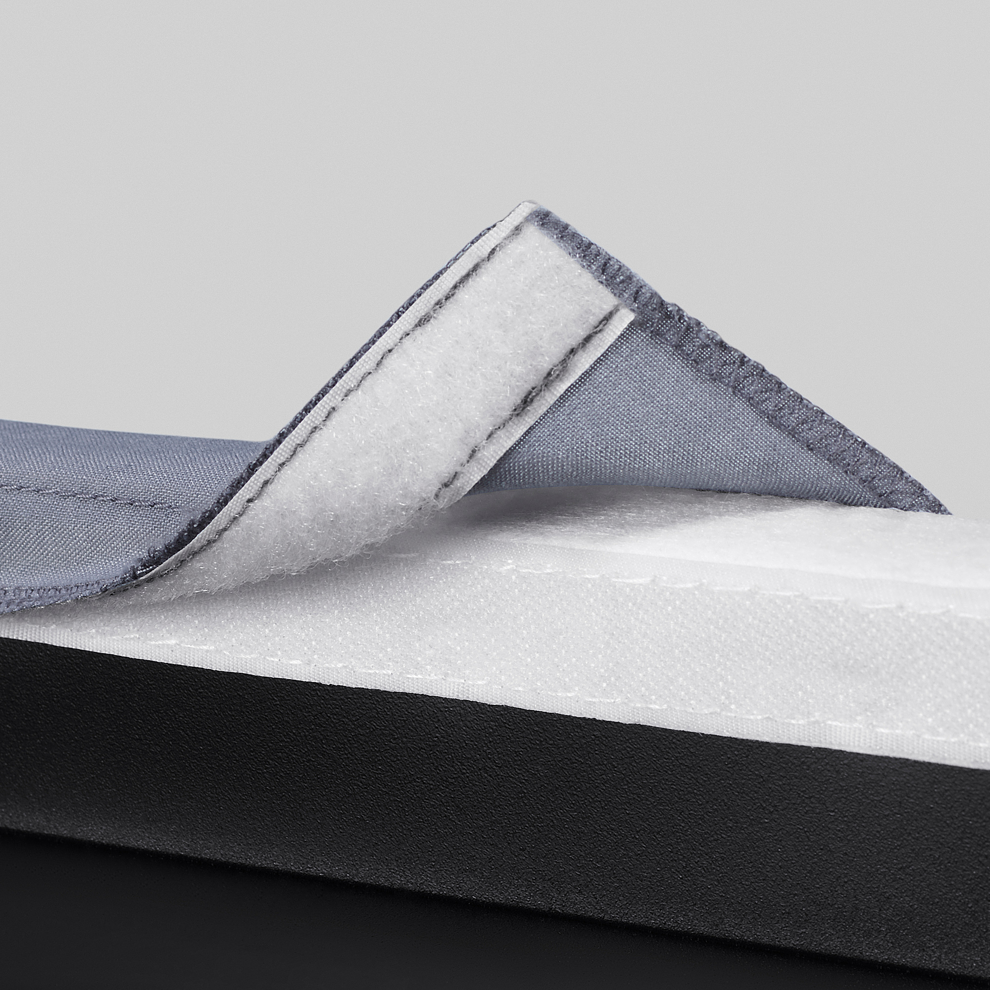Detailní záběr odolného polštáře na židli se zapínáním na suchý zip, který ukazuje jeho kvalitní prošívání a měkké polstrování.