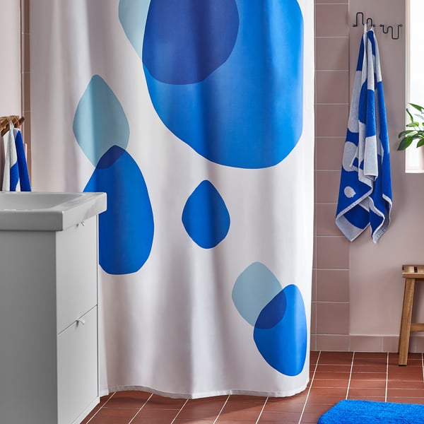 Modrý sprchový závěs BERGVATTNET se vzory, v blízkosti umyvadla. Recyklovaný polyester, vodoodpudivý.