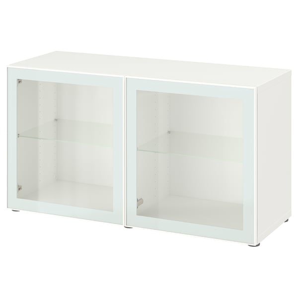 Bílá skříňka ikea BESTÅ se skleněnými dvířky a policemi. Má obdélníkový tvar a minimalistický design.