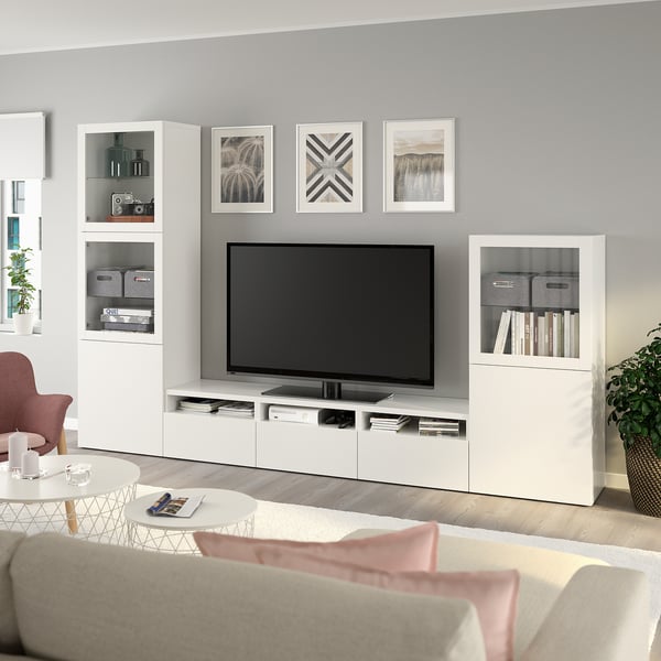 Moderní obývací pokoj s TV na BESTÅ linky, knihami, růžovými polštáři, minimalistickým designem.