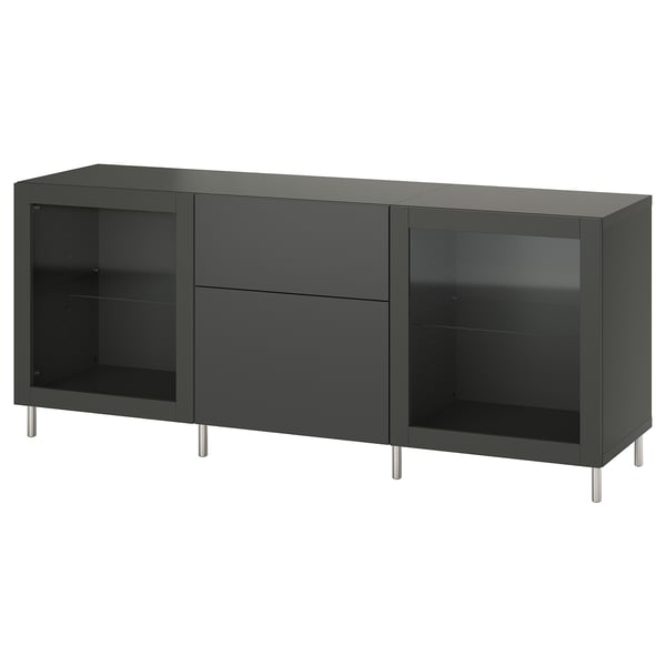 Úložný díl IKEA BESTÅ v tmavě šedé barvě se skleněnými dvířky a kovovými nohami. Má nastavitelné police, dvě zásuvky a moderní, elegantní design.