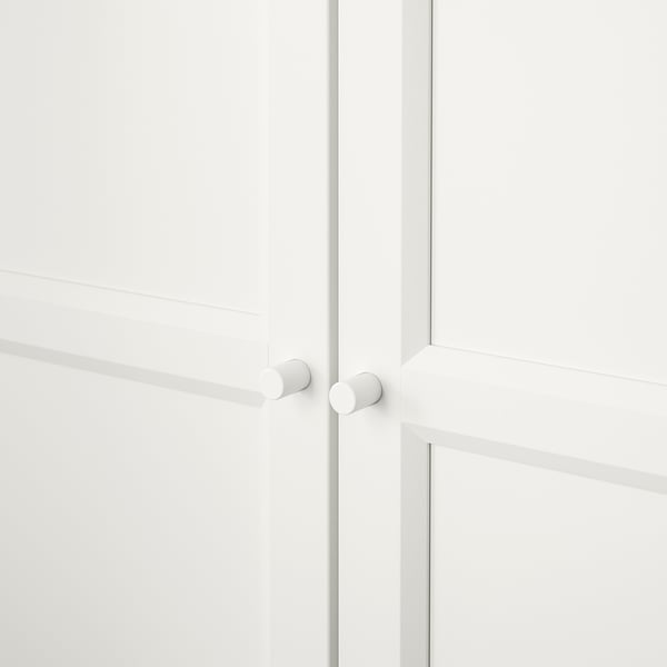 Minimalistická bílá skříň se zaoblenými knoflíky, zavřenými dvířky a bezešvými spoji.