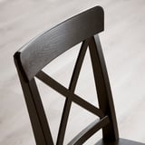 Opěradlo židle z tmavého dřeva s elegantním, zakřiveným designem. Robustní, leštěný povrch a viditelná kresba dřeva. Pevná, hranatá konstrukce podpírá sedadlo.