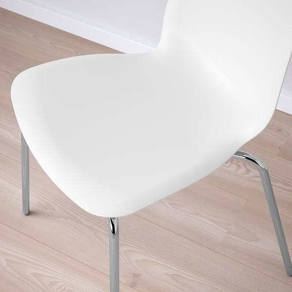 Moderní bílá židle s elegantními chromovanými nohami na dřevěné podlaze.