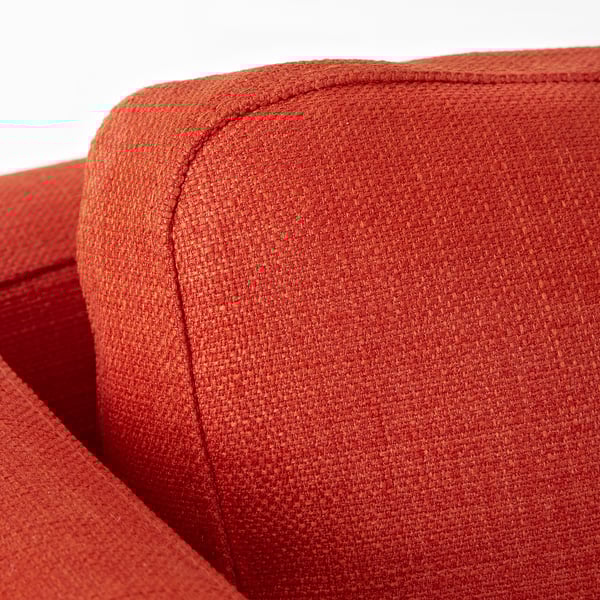 Detailní záběr na oranžovou židli z měkké látky, která předvádí její robustní prošívání a plyšovou texturu.