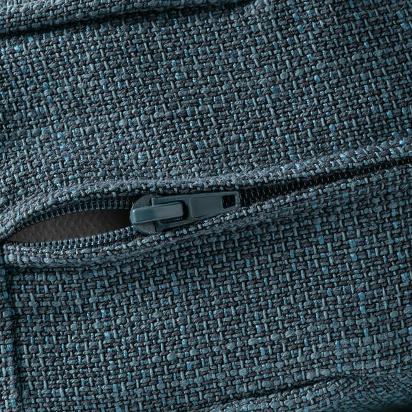Detail zipu na texturované, šedomodré látce, pravděpodobně potahu pohovky.