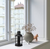 Okenní parapet: černá lucerna, sušené květiny, dřevěný kůň. Lucerna od ENRUM, malá a elegantní.