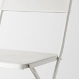 Moderní, minimalistická bílá skládací židle, vyrobená z odolné oceli s práškovým nástřikem a plastu, zobrazená zblízka.