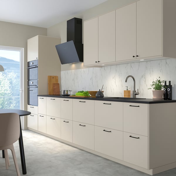 Moderní kuchyňská linka s bílou troubou FINSMAKARE, elegantními pracovními deskami, černými klikami, šedou podlahou a velkým oknem.
