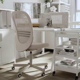 Moderní bílá domácí kancelář. Jeho součástí je ergonomická židle FLINTAN, bílý psací stůl a bílá knihovna s knihami a psacími potřebami.