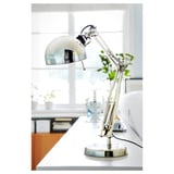 Elegantní, nastavitelná ocelová stolní lampa, nakloněná tak, aby poskytovala směrové světlo.