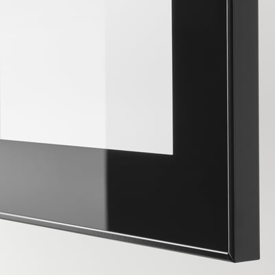 Detail lesklého černého rámu GLASSVIK s čirým sklem, které odráží světlo a ukazuje vysoce kvalitní povrchovou úpravu.