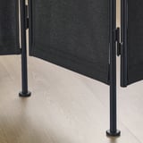 Moderní dělicí stěna s černými kovovými nohami a skládanými látkovými panely, která se vyznačuje robustní konstrukcí a elegantním designem.