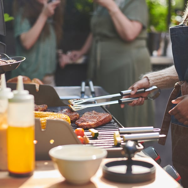 Grilovací scéna s nářadím a jídlem na grilu.