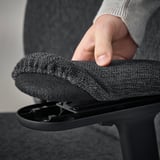 Nastavitelné područky na kancelářské židli GRÖNFJÄLL. 3D nastavitelnou loketní opěrku svírá ruka, která demonstruje ergonomickou oporu.