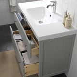 Moderní koupelnová umyvadlová skříňka se zásuvkami, s čistými liniemi, hladce výsuvnými zásuvkami a vestavěným sifonem.