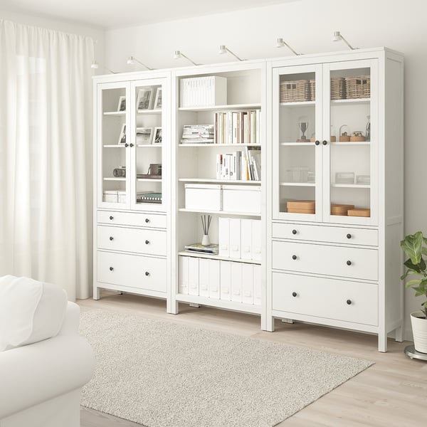Kombinace HEMNES: skleněné dveře, zásuvky, knihy, rostlina, koberec, pohovka.
