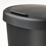 Černý plastový koš s víkem, kulatým designem a malými okrajovými otvory pro upevnění sáčků.
