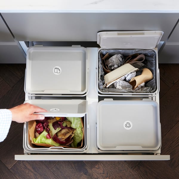 Čtyři otevřené odpadkové koše označené pro různé druhy odpadu, včetně kompostovatelných a recyklovatelných.