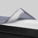 Detail materiálu podušky židle: měkká bílá pěna s šedým látkovým potahem.